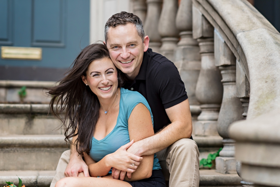 An engaged man and woman sit on the stoop of a house next to Rittenhouse Square.